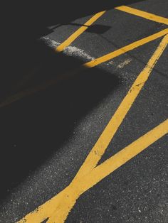 an empty parking lot with yellow lines painted on the pavement and a stop sign in the distance