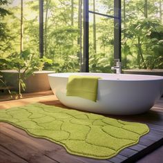 a bath tub sitting on top of a wooden floor next to a green rug in front of a window