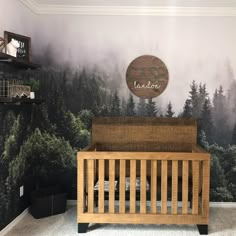 a wooden crib sitting in front of a forest mural