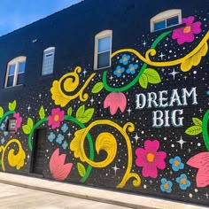 a mural on the side of a building that says dream big with flowers and stars