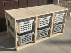 three white plastic baskets sitting on top of a wooden shelf next to a building with brown doors