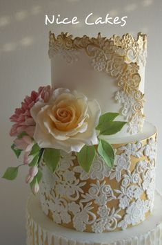 there is a three layer cake with flowers on the top and bottom tiers that are gold, white, and pink