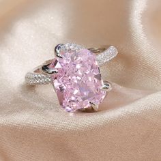 a fancy pink diamond ring sitting on top of a white cloth