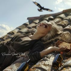 a woman laying on top of a tiled roof next to a bird flying over her