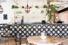 the interior of a restaurant with tables, chairs and bar stools in black and white tiles