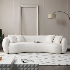 a white couch sitting on top of a floor next to a table and potted plant