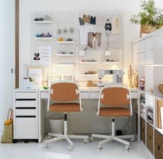 two office chairs sitting at a desk in front of a wall with pictures on it