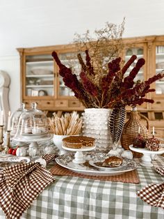 a table topped with plates and dishes covered in fall decorating items on top of a checkered table cloth