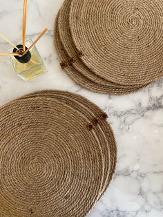 two round placemats sitting on top of a white marble counter next to a bottle of perfume