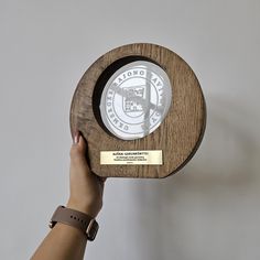 a person holding up a wooden plaque with the seal on it