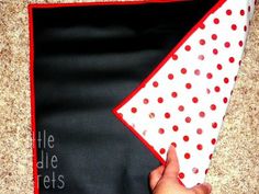 a hand is holding a piece of cloth with red and white polka dots on it