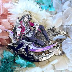 two anime pin badges sitting on top of some white and blue flowers with pink petals in the background