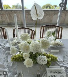 the table is set with white flowers and silverware