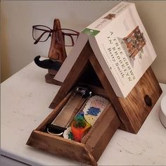 an open wooden box on top of a table with glasses and other items in it