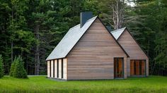 a small wooden house in the middle of a field with lots of trees around it