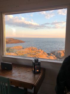 a table with a lantern on it in front of a window looking out at the ocean