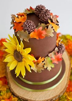 a three tiered chocolate cake decorated with sunflowers and leaves