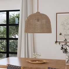 a wooden table with two glasses on it and a hanging light over it in front of a window