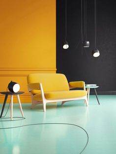 a yellow chair sitting next to a table on top of a hard wood floor in front of a black wall