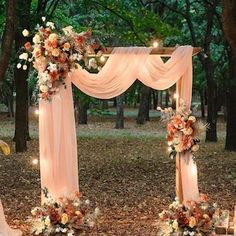 an outdoor wedding set up in the woods with flowers and candles on the ground, surrounded by trees