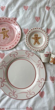 pink and white plates with gingerbread cookies on them, sitting on a bed covered in hearts