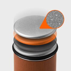 an orange and silver canister sitting on top of a wooden table