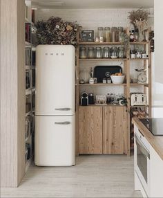 a white refrigerator freezer sitting inside of a kitchen next to a wooden shelf filled with pots and pans