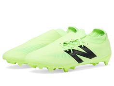 a neon green soccer shoe with black and white lettering on the sole, in front of a