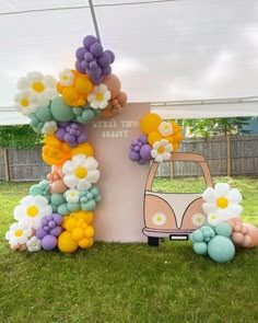 an outdoor area with balloons and flowers on the grass, including a vw bus