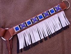 a brown leather belt with fringes and beads on the side, sitting on a leopard print background