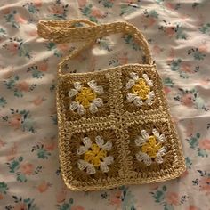 a crocheted purse sitting on top of a bed covered in floral print sheets