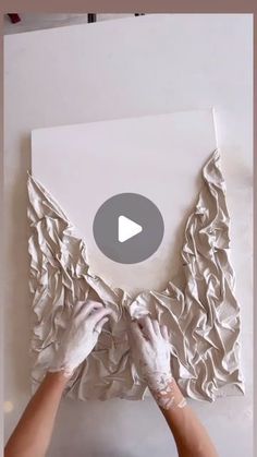 two hands are working on a piece of paper that is being made into a sculpture