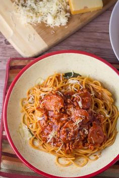 a plate of spaghetti with meat sauce and grated parmesan cheese on the side