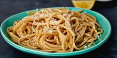 a blue bowl filled with pasta and parmesan cheese on top of a table