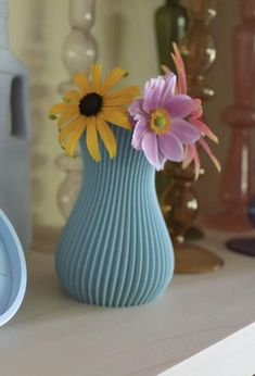 there is a blue vase with flowers in it on the shelf next to a clock