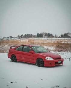 a red car is parked in the snow