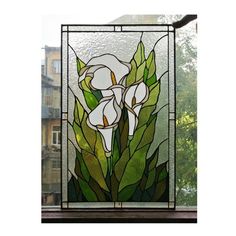 a stained glass window with white flowers in the center and green leaves on it, next to a building