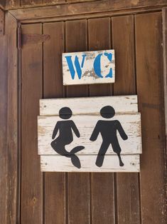 a wooden sign on the side of a building that says w c and two people