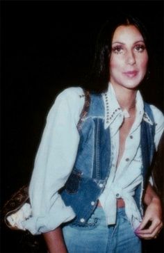 a young woman is posing for the camera in her denim vest and shirt with pearls on it