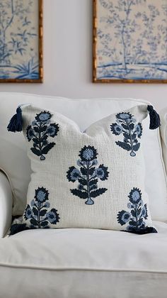 a white couch with blue flowers on it and two framed pictures above the back wall