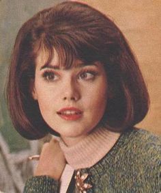 a woman with short hair wearing a sweater