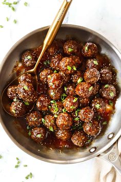 meatballs are being cooked in a pan with a spoon and garnished with parsley