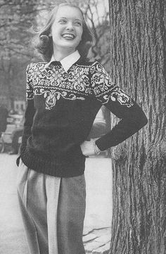 an old black and white photo of a woman standing next to a tree with her hands on her hips