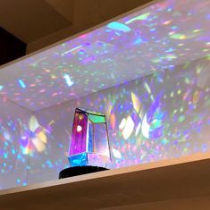 a colorful vase sitting on top of a table under a projector screen in a room