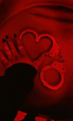 a woman laying on her stomach with handcuffs and heart shaped cutouts in red light