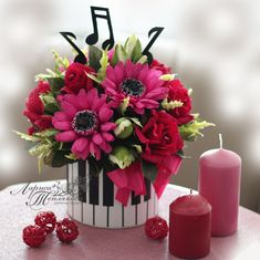 a vase filled with red and pink flowers next to a candle on top of a table