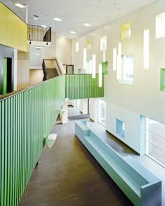 the inside of a building with green and white walls, stairs, and windows on both sides