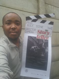 a man holding up a movie poster in front of a wall with the words'mr story teller'written on it