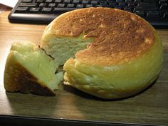 a piece of bread sitting on top of a wooden table next to a keyboard