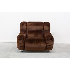 a brown reclining chair sitting on top of a cement floor next to a white wall